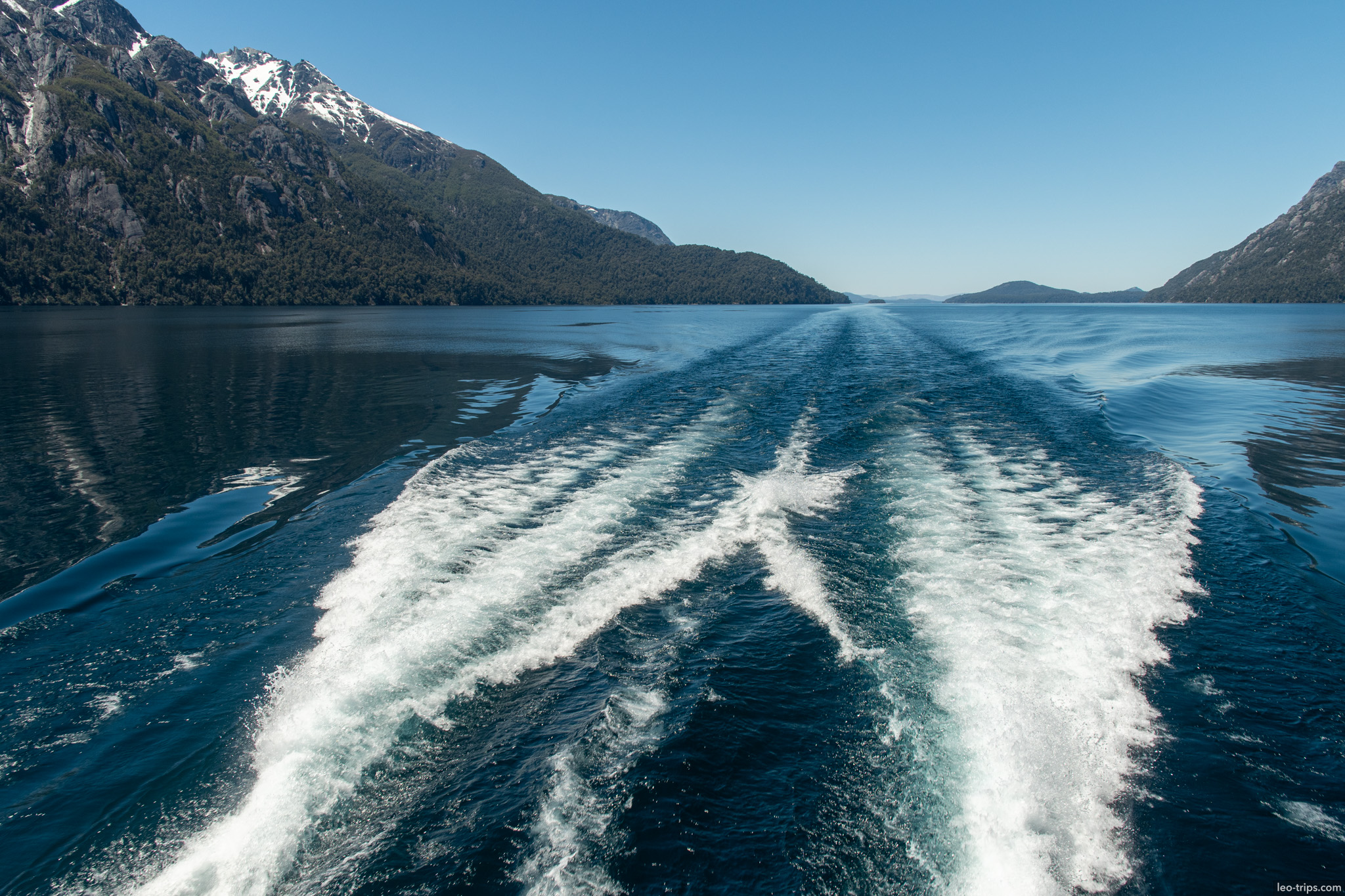 boat wake trailing toward mountains puerto blest