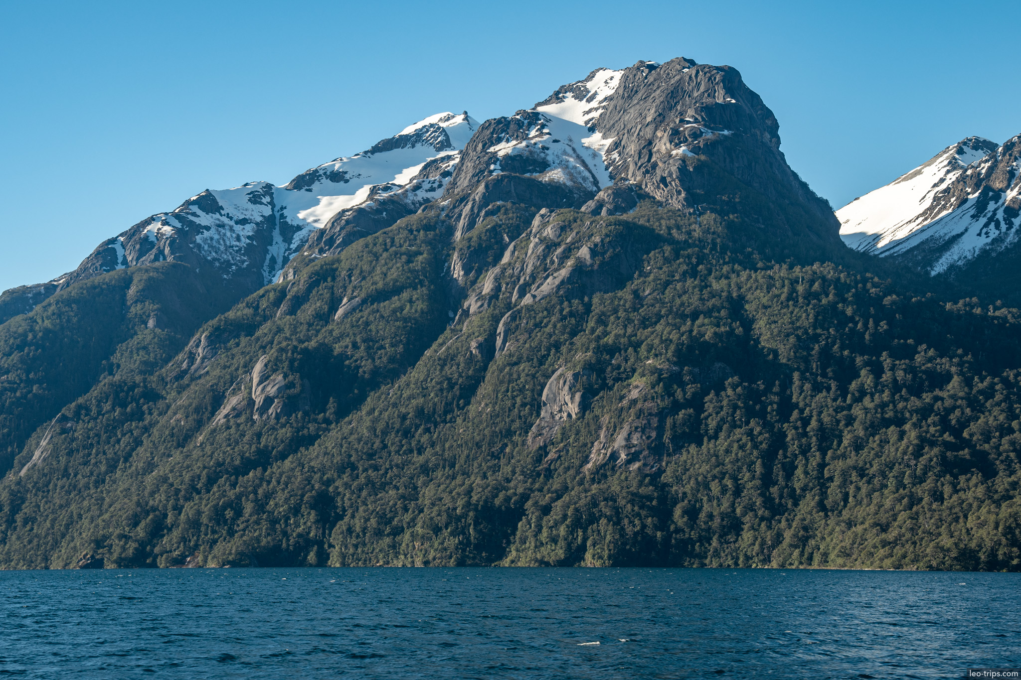 snowy peak above forested cliffs puerto blest