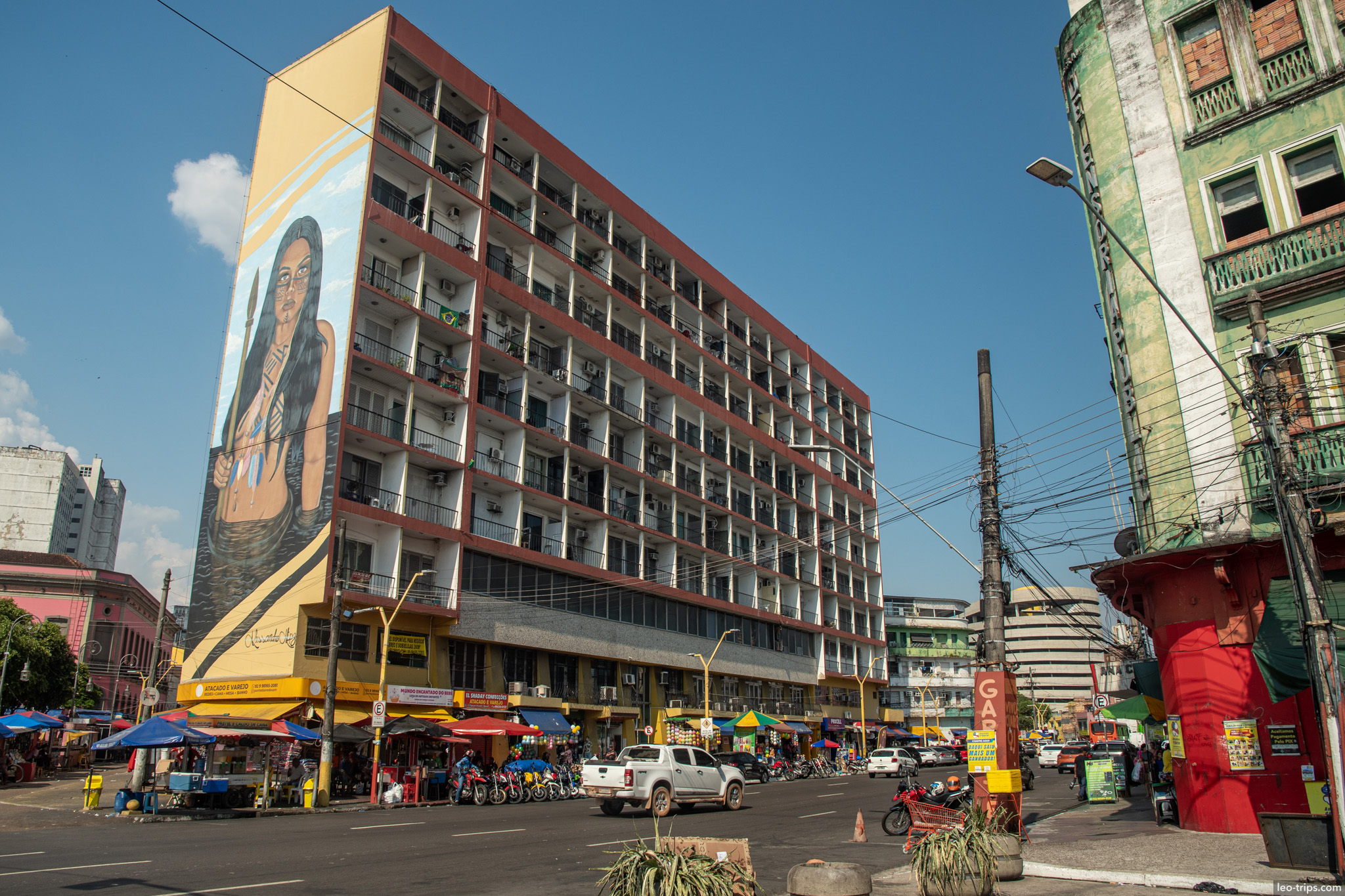 A tall apartment building in the city center adorned with a large vertical mural, showcasing the city's embrace of street art