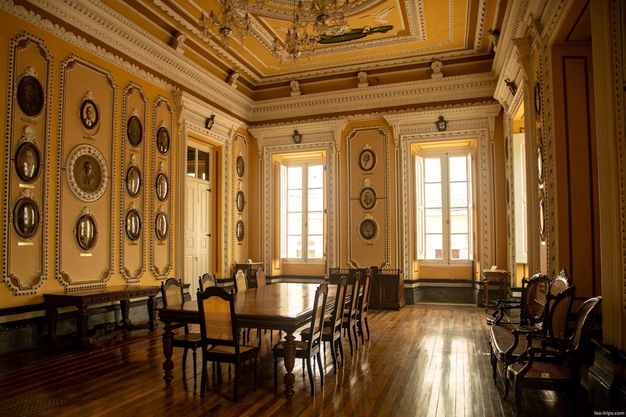 The elegant interior of a historic palace hall, featuring a long wooden conference table, period furniture, and high ceilings