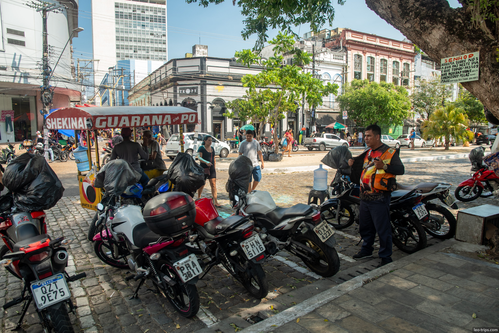 A typical urban scene in Manaus showing parked motorcycles and a street vendor stall selling traditional Guaraná
