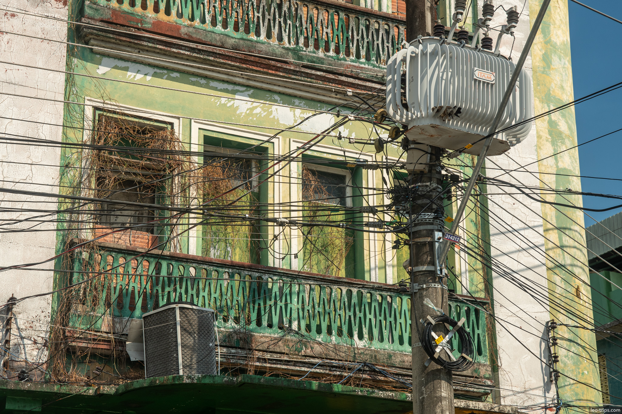 A close-up look at the urban texture of Manaus: a chaotic tangle of overhead electrical wires in front of an old, weathered building facade