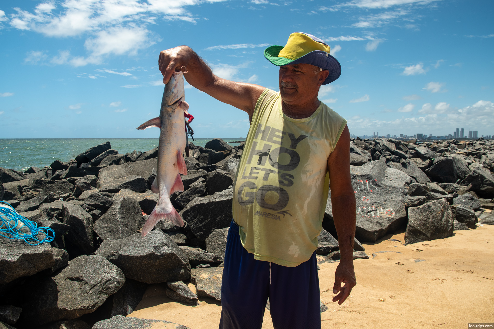 fisherman holding caught shark on rocky breakwater olinda