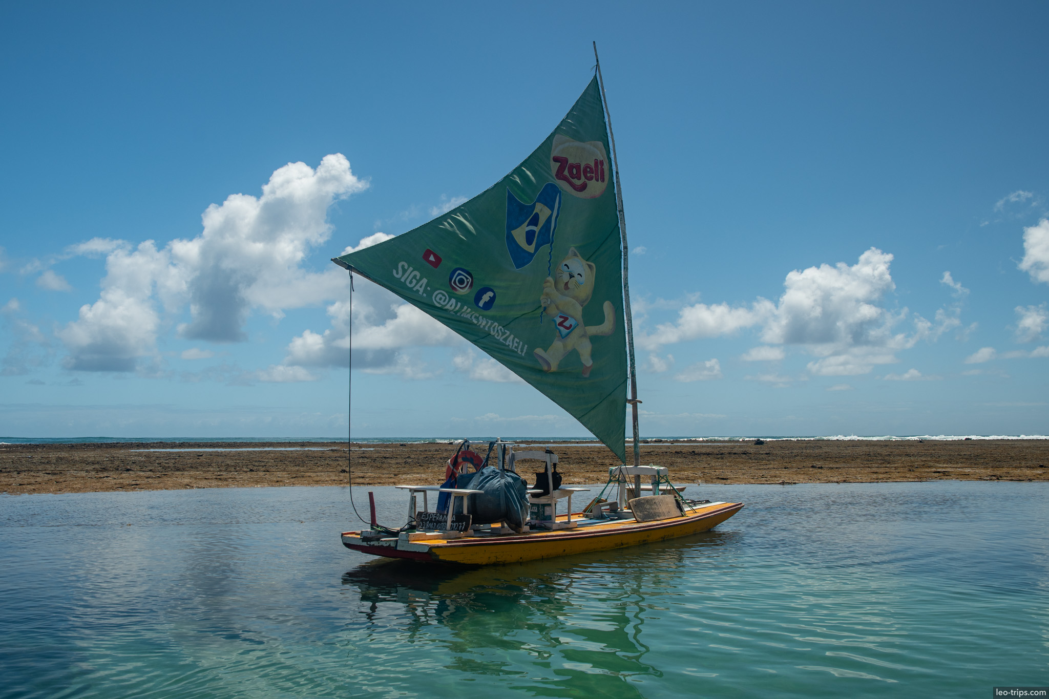 jangada green sail yellow hull on reef flat porto de galinhas