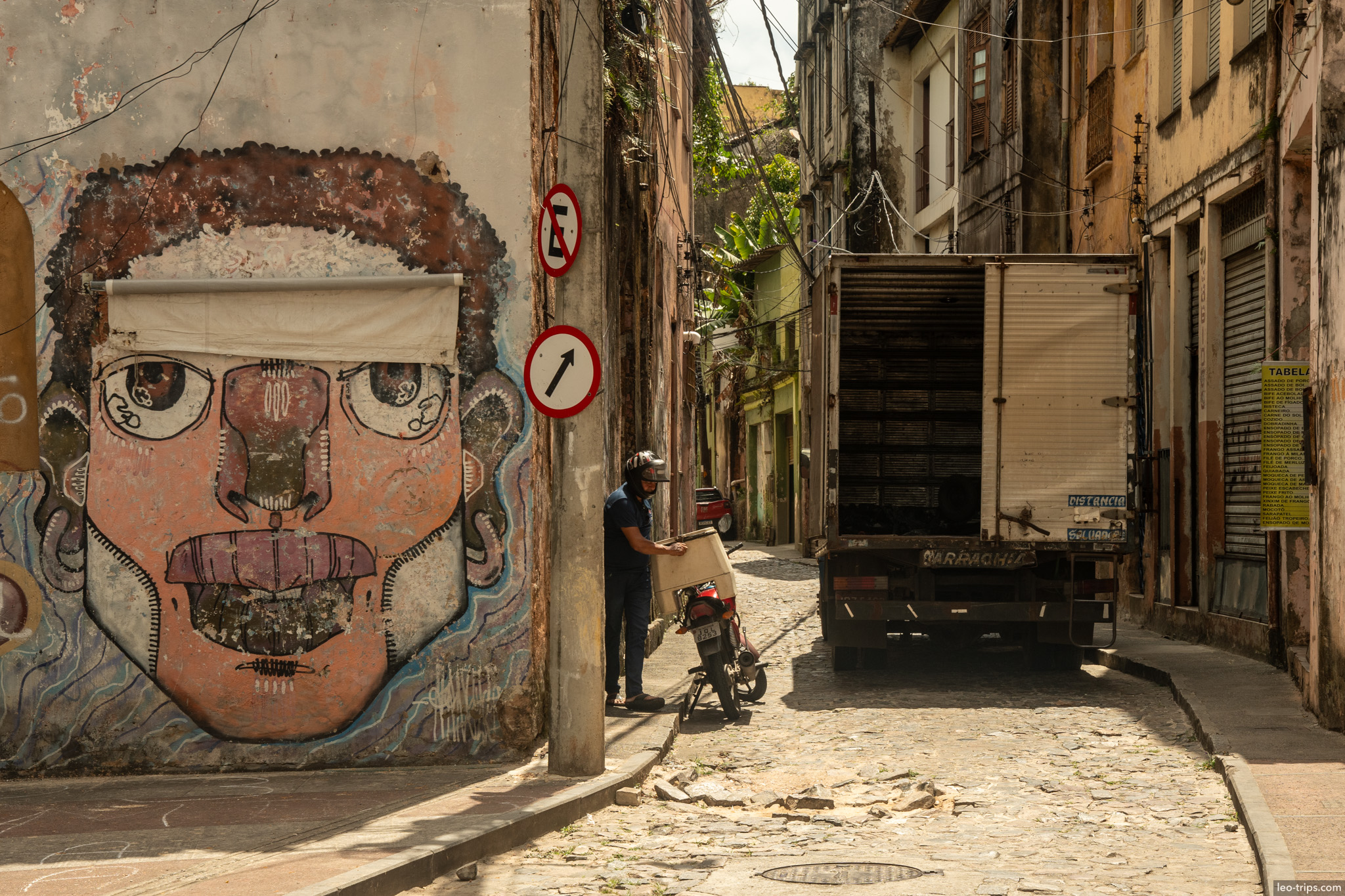 large face mural narrow alley truck motorcycle salvador salvador