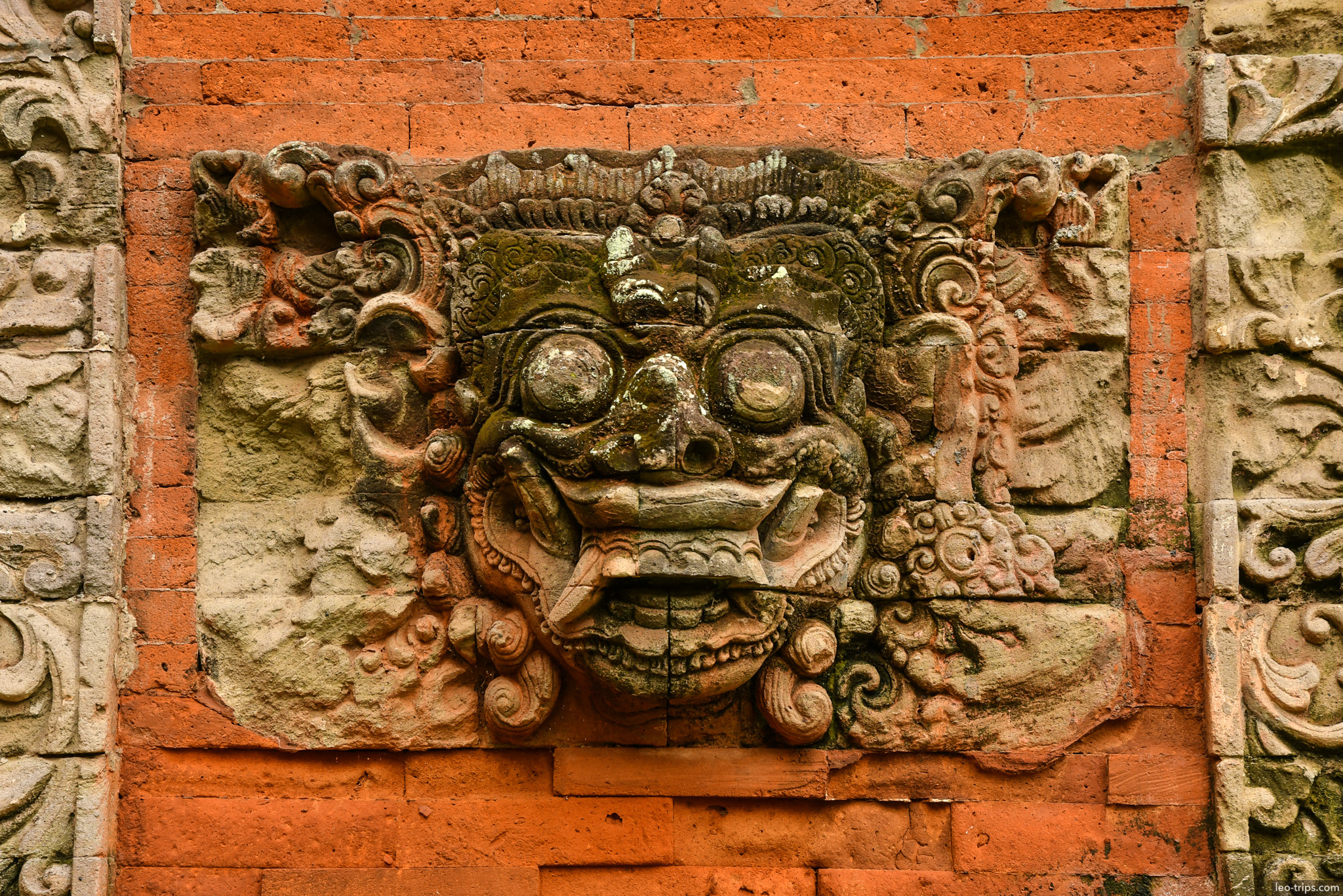 bhoma face relief carved in red brick wall bali