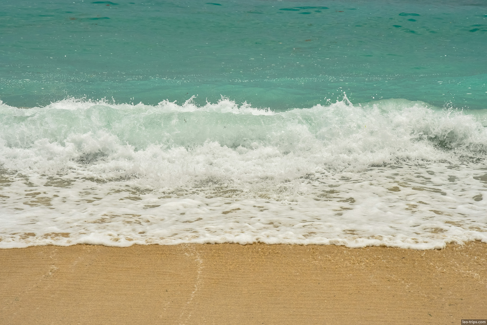 turquoise wave crashing on sandy shore bali