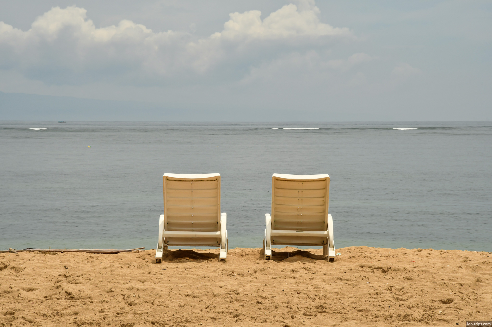 two empty lounge chairs facing ocean bali