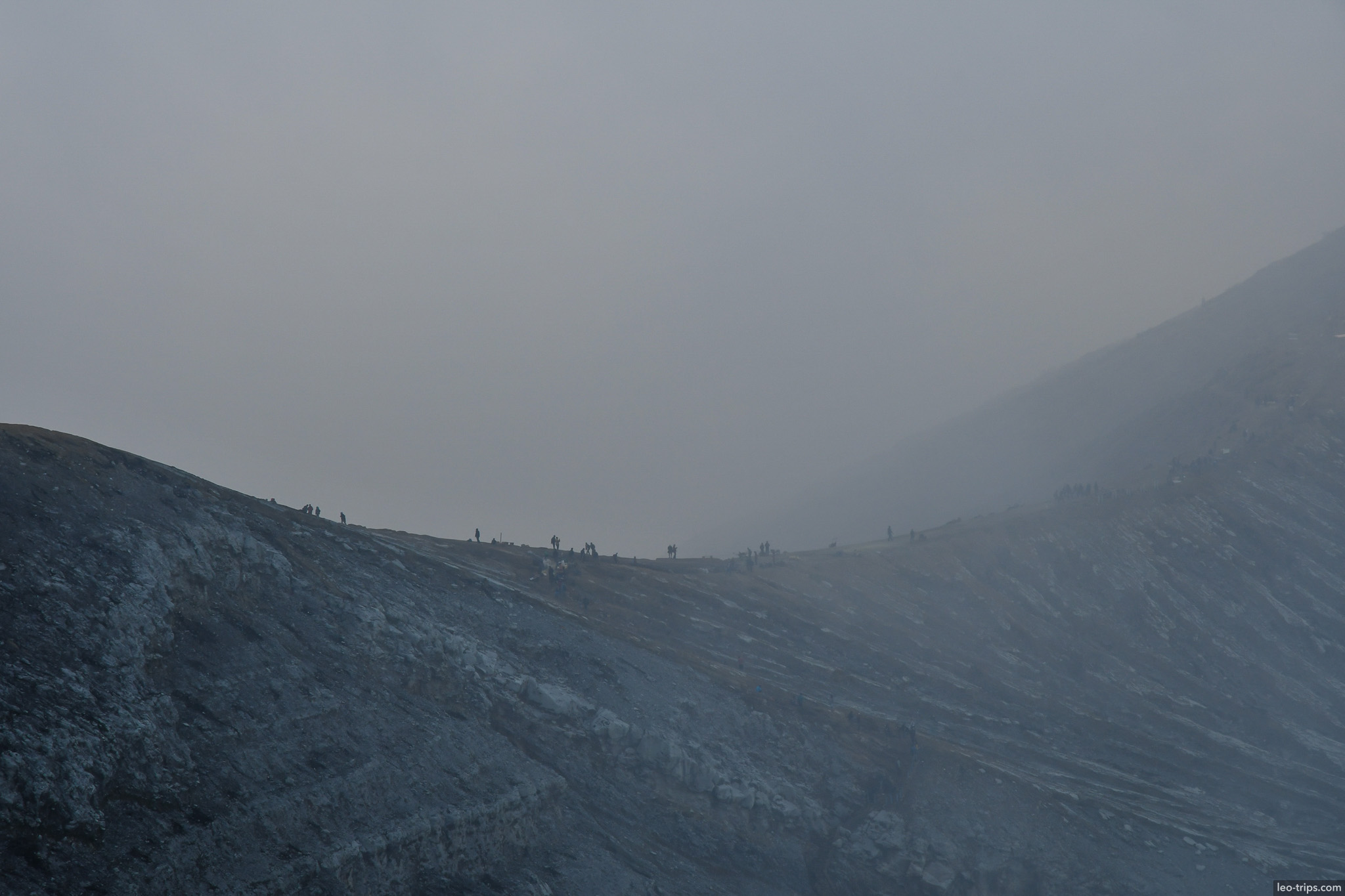 hikers on distant crater ridge in fog ijen ijen lake