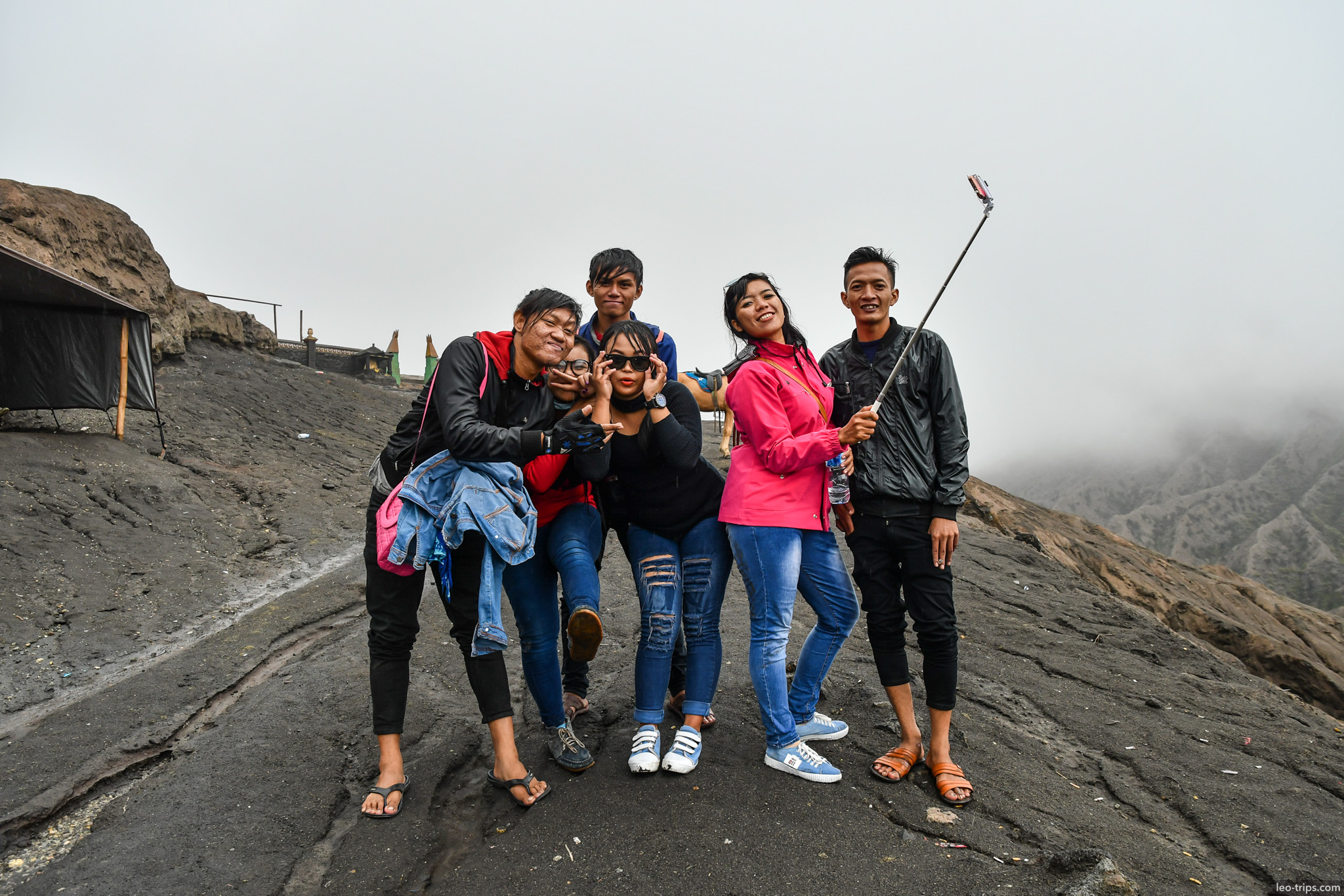 tourists taking selfie on bromo crater rim mount bromo
