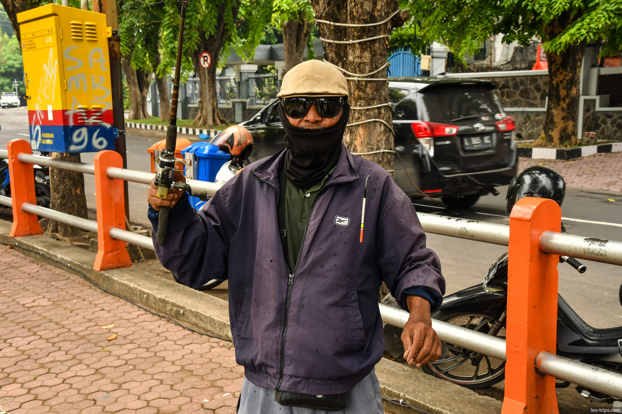 man with fishing rod sunglasses mask street surabaya