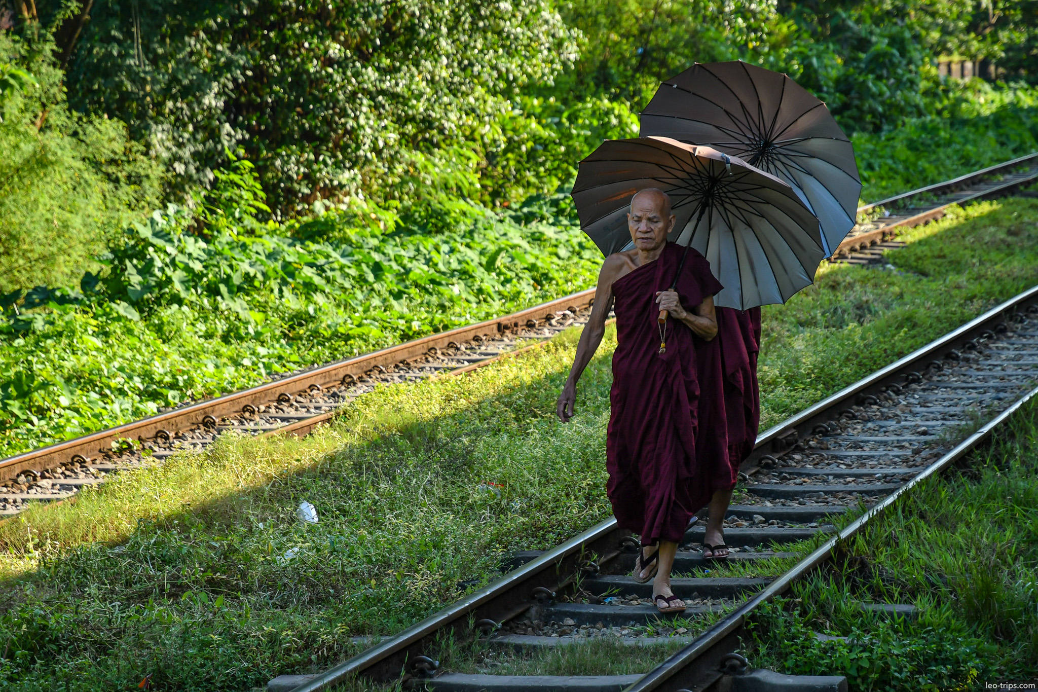 yangon buddhist monk with umbrella walking railway tracks yangon