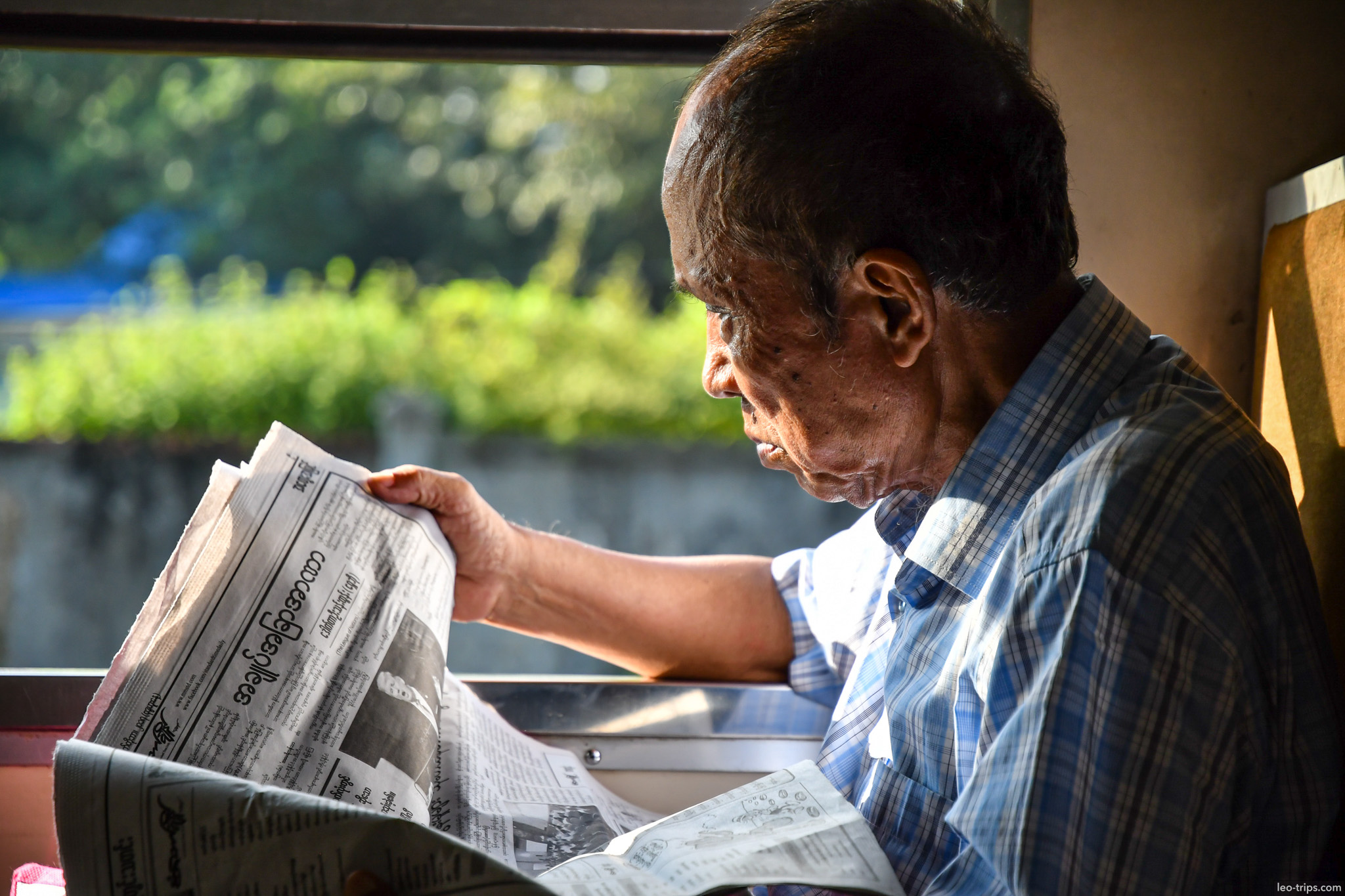 yangon elderly man reading newspaper train window yangon