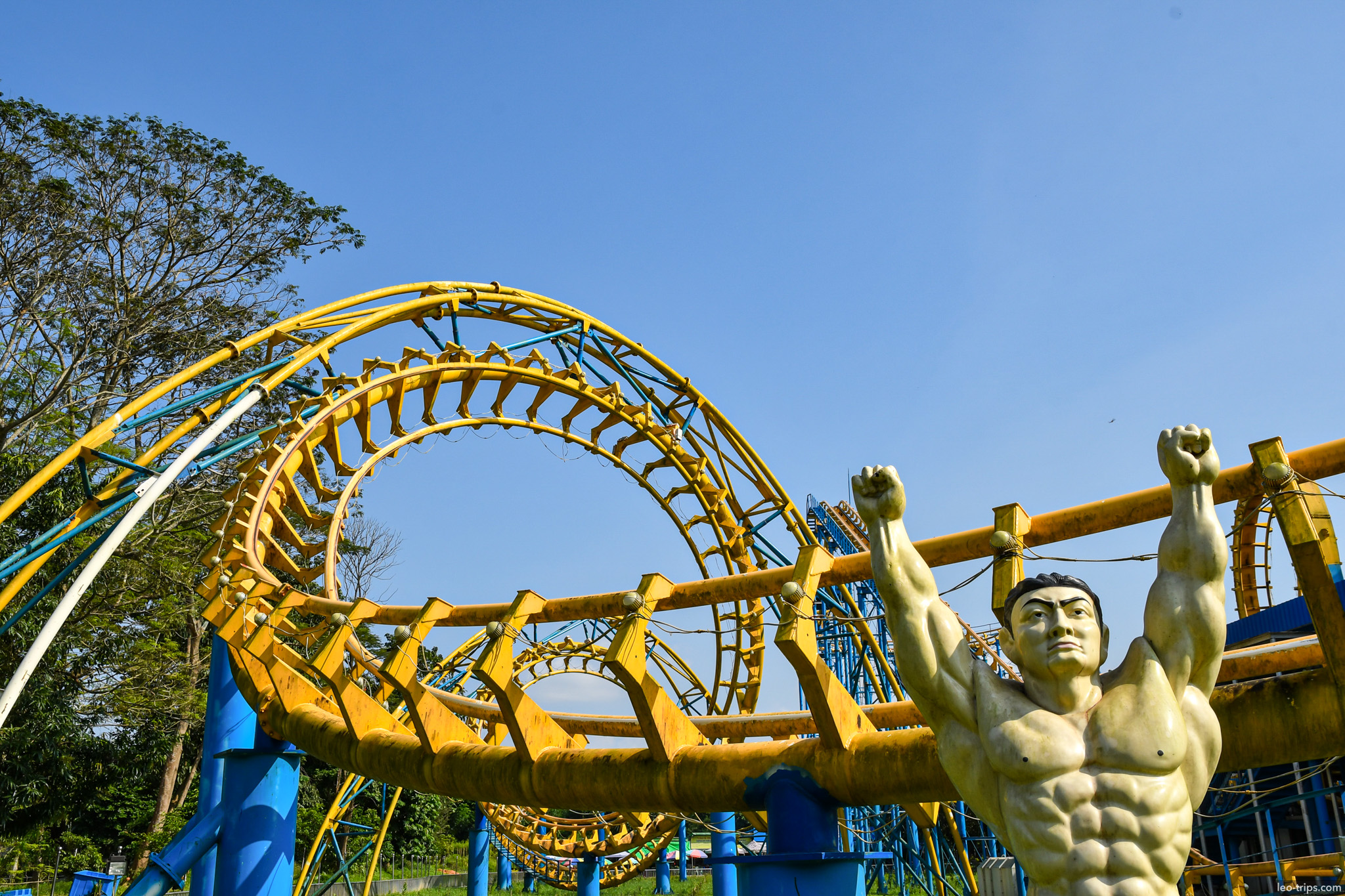 yellow roller coaster loop with muscular statue yangon