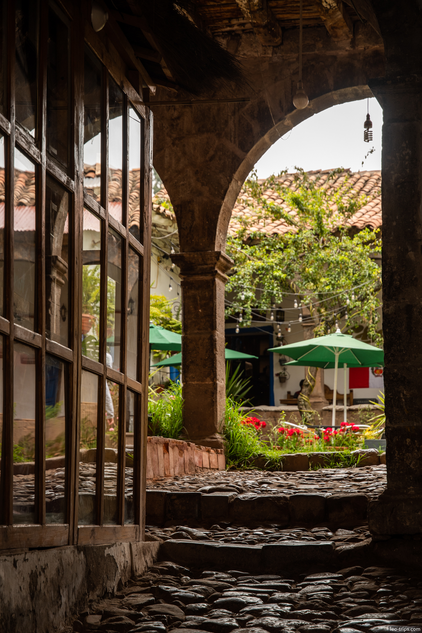 colonial courtyard arch cobblestone green umbrellas cusco