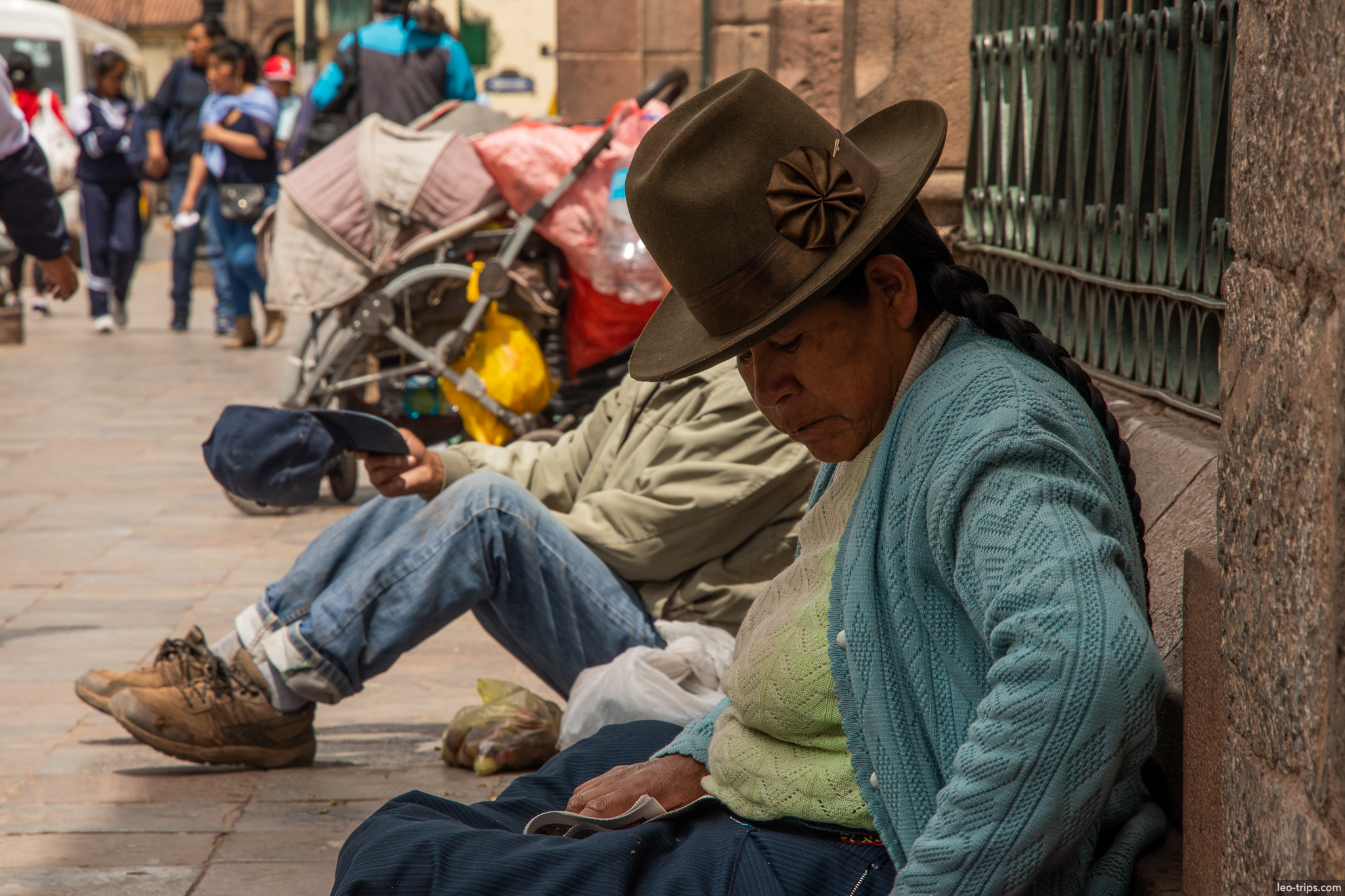 quechua woman hat sitting sidewalk phone cusco