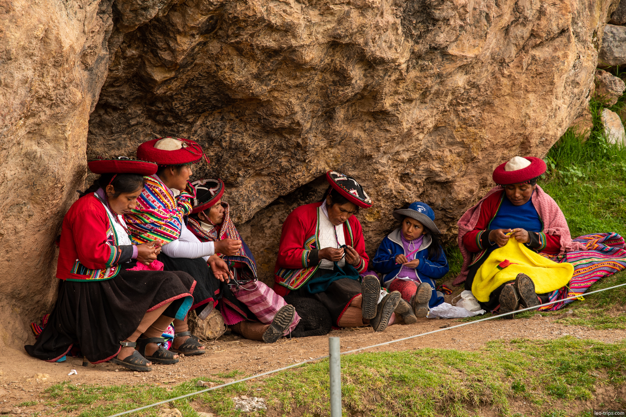 quechua women knitting traditional dress by rock cusco