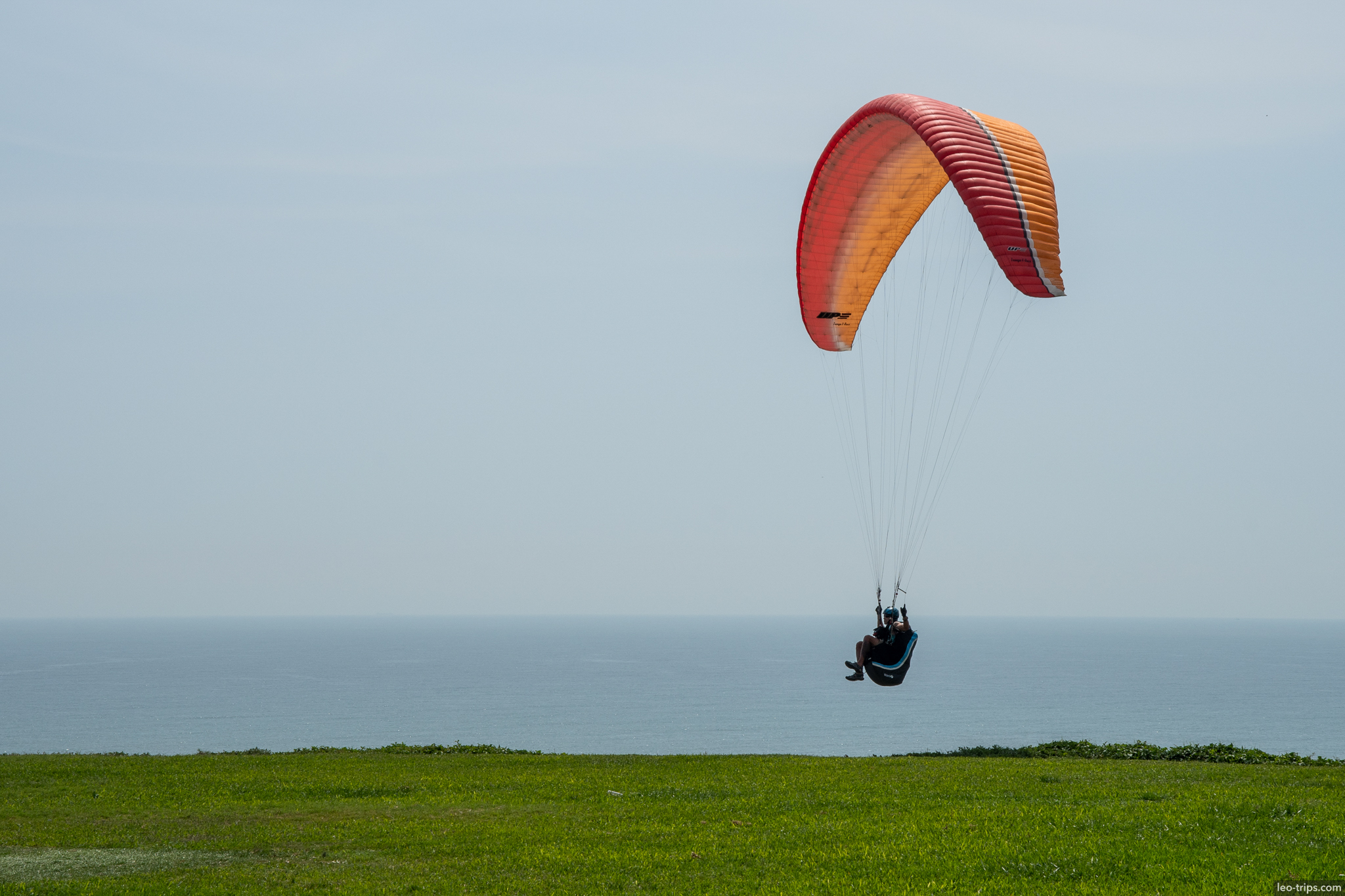 paragliding red orange canopy pacific ocean lima